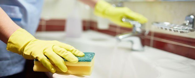 person using gloves and sponge to scrub sink