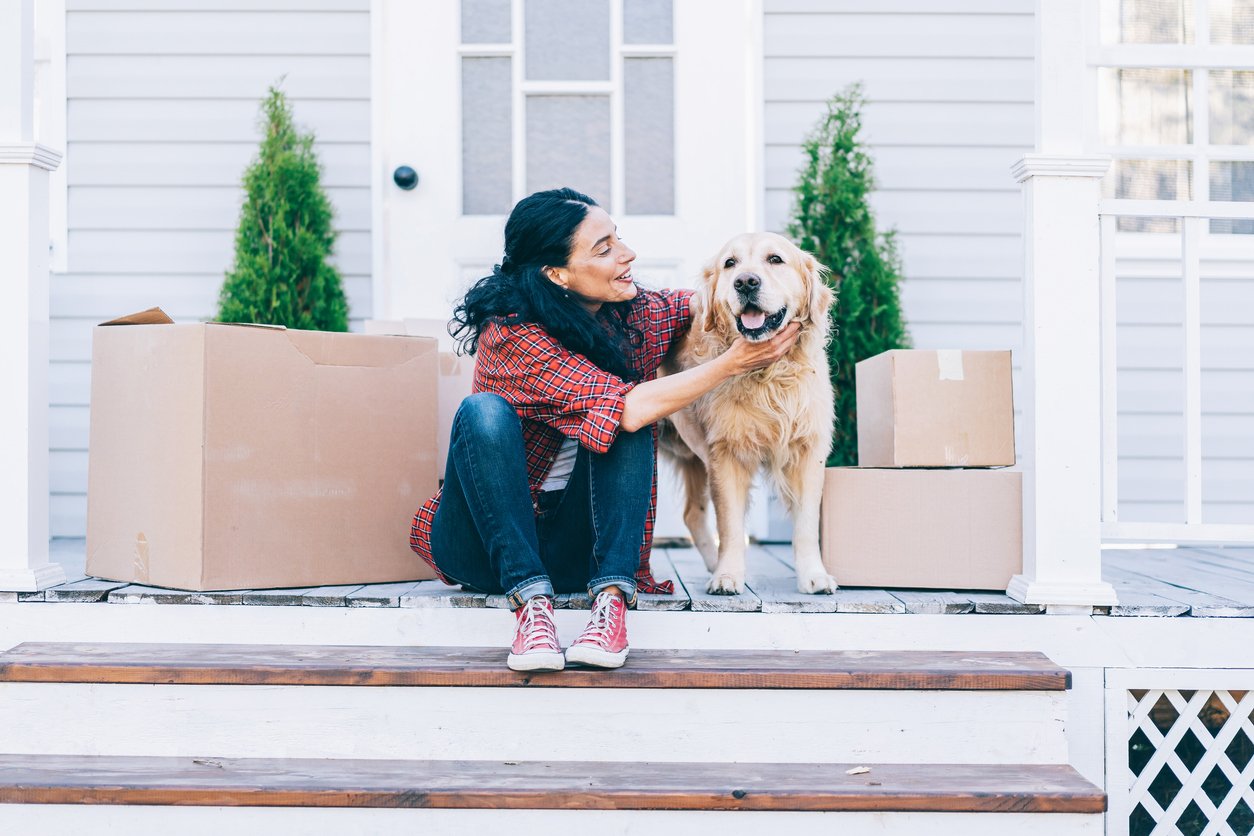 woman on porch with moving boxes and her golden retriever