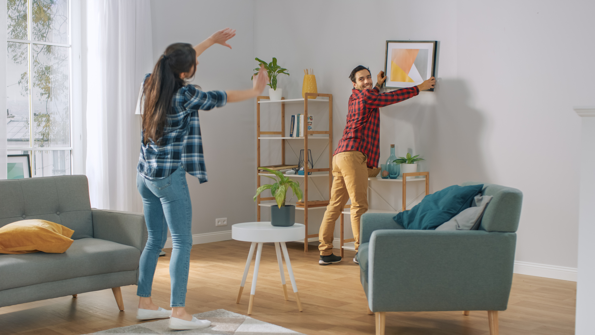 couple hanging new picture frame on wall